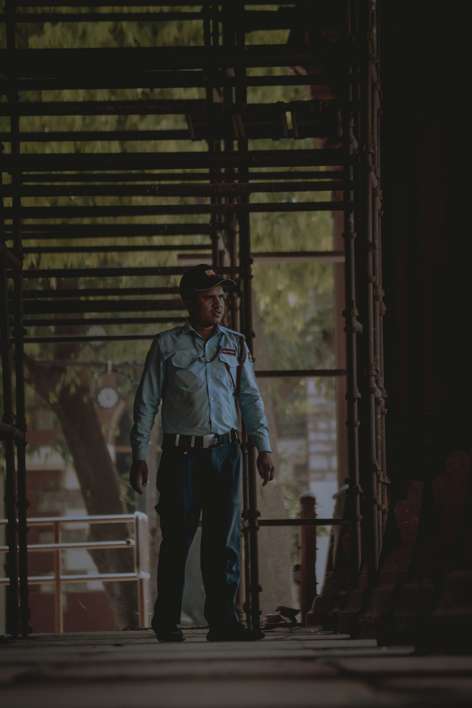 Security guard patrolling a scaffolded construction site at dusk